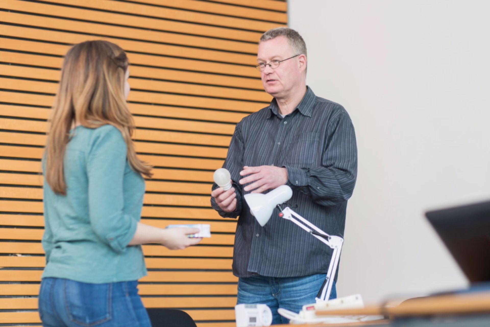 Ein Stromspar-Helfer der KEK zeigt einer Kundin eine LED-Leuchte.