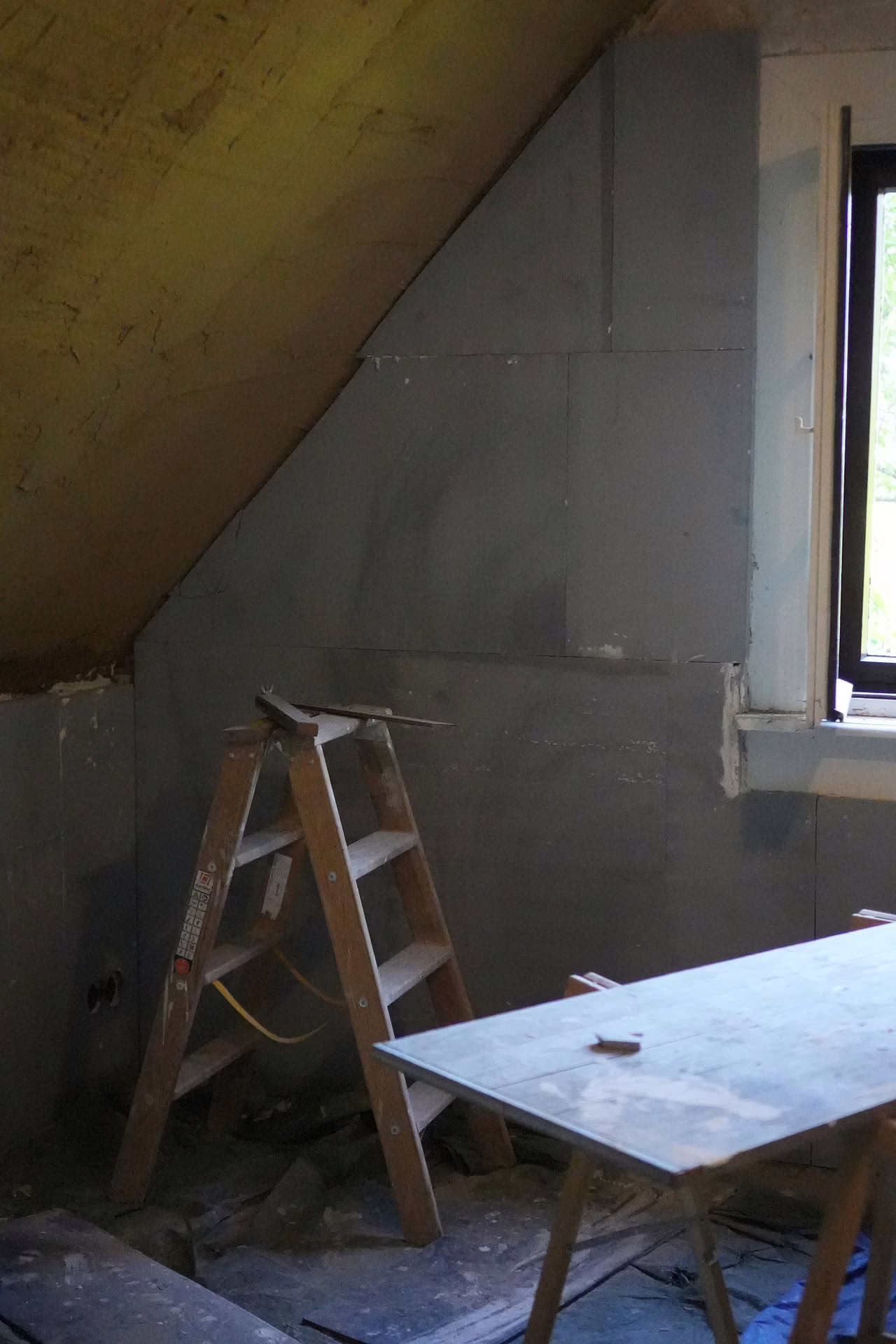 Die Wands ist ferti verputzt. Vor der Wand steht eine Leiter.