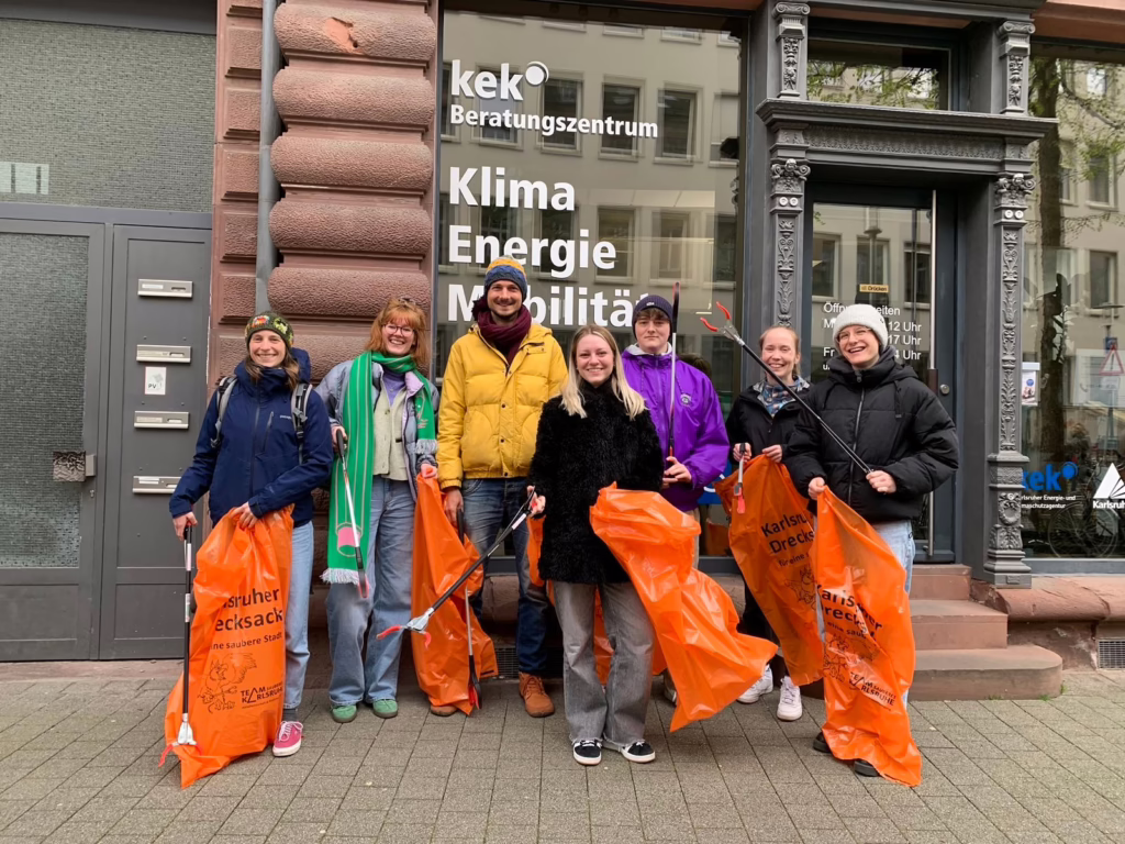 Mitarbeitende der KEK stehen vor dem Beratungszentrum mit Greifzangen und Müllsäcken in der Hand.