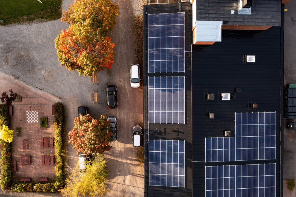 Auf dem Bild ist ein großes Haus von oben zu sehen. Auf dem Dach des Hauses sind Photovoltaik-Module zu sehen.