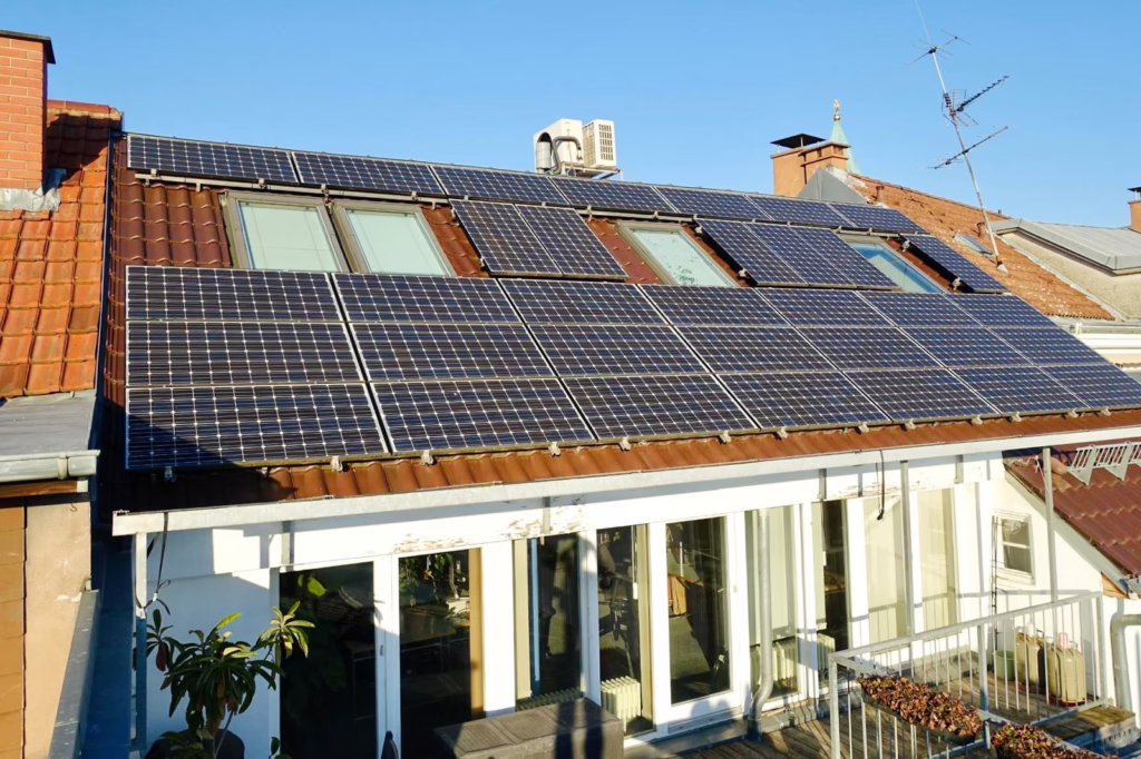 Bild eines Daches, das mit Photovoltaik belegt ist. Der Himmel ist blau und sonnig.